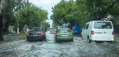 Odessa, Ukrayna -9 Ağustos 2019: sağanak yağışların neden olduğu sel felaketi sırasında su lar altında kalan yolda araba sürmek. Arabalar su üzerinde yüzüyor, sokakları su basayor. Arabaya sıçrat. Büyük bir su birikintisi ile sular altında şehir yolu