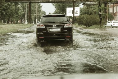 Odessa, Ukrayna -9 Ağustos 2019: sağanak yağışların neden olduğu sel felaketi sırasında su lar altında kalan yolda araba sürmek. Arabalar su üzerinde yüzüyor, sokakları su basayor. Arabaya sıçrat. Büyük bir su birikintisi ile sular altında şehir yolu