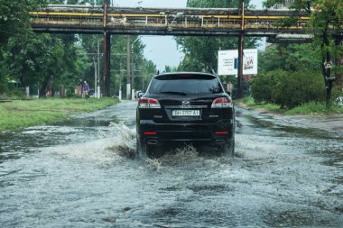 Odessa, Ukrayna -9 Ağustos 2019: sağanak yağışların neden olduğu sel felaketi sırasında su lar altında kalan yolda araba sürmek. Arabalar su üzerinde yüzüyor, sokakları su basayor. Arabaya sıçrat. Büyük bir su birikintisi ile sular altında şehir yolu