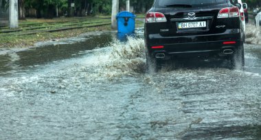 Odessa, Ukrayna -9 Ağustos 2019: sağanak yağışların neden olduğu sel felaketi sırasında su lar altında kalan yolda araba sürmek. Arabalar su üzerinde yüzüyor, sokakları su basayor. Arabaya sıçrat. Büyük bir su birikintisi ile sular altında şehir yolu