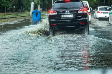 Odessa, Ukrayna -9 Ağustos 2019: sağanak yağışların neden olduğu sel felaketi sırasında su lar altında kalan yolda araba sürmek. Arabalar su üzerinde yüzüyor, sokakları su basayor. Arabaya sıçrat. Büyük bir su birikintisi ile sular altında şehir yolu