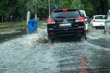 Odessa, Ukrayna -9 Ağustos 2019: sağanak yağışların neden olduğu sel felaketi sırasında su lar altında kalan yolda araba sürmek. Arabalar su üzerinde yüzüyor, sokakları su basayor. Arabaya sıçrat. Büyük bir su birikintisi ile sular altında şehir yolu