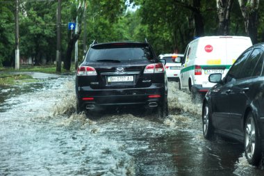 Odessa, Ukrayna -9 Ağustos 2019: sağanak yağışların neden olduğu sel felaketi sırasında su lar altında kalan yolda araba sürmek. Arabalar su üzerinde yüzüyor, sokakları su basayor. Arabaya sıçrat. Büyük bir su birikintisi ile sular altında şehir yolu