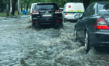 Odessa, Ukrayna -9 Ağustos 2019: sağanak yağışların neden olduğu sel felaketi sırasında su lar altında kalan yolda araba sürmek. Arabalar su üzerinde yüzüyor, sokakları su basayor. Arabaya sıçrat. Büyük bir su birikintisi ile sular altında şehir yolu