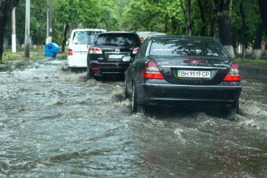Odessa, Ukrayna -9 Ağustos 2019: sağanak yağışların neden olduğu sel felaketi sırasında su lar altında kalan yolda araba sürmek. Arabalar su üzerinde yüzüyor, sokakları su basayor. Arabaya sıçrat. Büyük bir su birikintisi ile sular altında şehir yolu