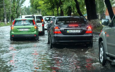 Odessa, Ukrayna -9 Ağustos 2019: sağanak yağışların neden olduğu sel felaketi sırasında su lar altında kalan yolda araba sürmek. Arabalar su üzerinde yüzüyor, sokakları su basayor. Arabaya sıçrat. Büyük bir su birikintisi ile sular altında şehir yolu