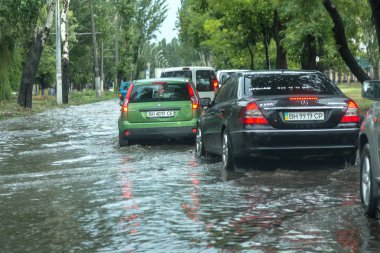 Odessa, Ukrayna -9 Ağustos 2019: sağanak yağışların neden olduğu sel felaketi sırasında su lar altında kalan yolda araba sürmek. Arabalar su üzerinde yüzüyor, sokakları su basayor. Arabaya sıçrat. Büyük bir su birikintisi ile sular altında şehir yolu
