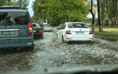 Odessa, Ukrayna -9 Ağustos 2019: sağanak yağışların neden olduğu sel felaketi sırasında su lar altında kalan yolda araba sürmek. Arabalar su üzerinde yüzüyor, sokakları su basayor. Arabaya sıçrat. Büyük bir su birikintisi ile sular altında şehir yolu