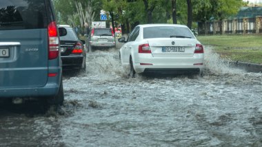 Odessa, Ukrayna -9 Ağustos 2019: sağanak yağışların neden olduğu sel felaketi sırasında su lar altında kalan yolda araba sürmek. Arabalar su üzerinde yüzüyor, sokakları su basayor. Arabaya sıçrat. Büyük bir su birikintisi ile sular altında şehir yolu
