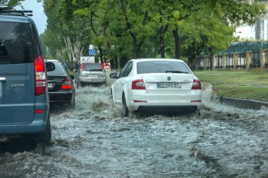 Odessa, Ukrayna -9 Ağustos 2019: sağanak yağışların neden olduğu sel felaketi sırasında su lar altında kalan yolda araba sürmek. Arabalar su üzerinde yüzüyor, sokakları su basayor. Arabaya sıçrat. Büyük bir su birikintisi ile sular altında şehir yolu