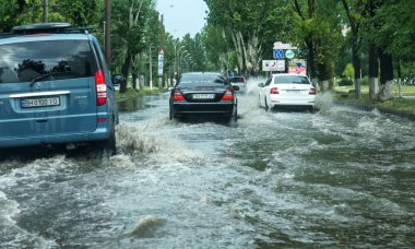Odessa, Ukrayna -9 Ağustos 2019: sağanak yağışların neden olduğu sel felaketi sırasında su lar altında kalan yolda araba sürmek. Arabalar su üzerinde yüzüyor, sokakları su basayor. Arabaya sıçrat. Büyük bir su birikintisi ile sular altında şehir yolu