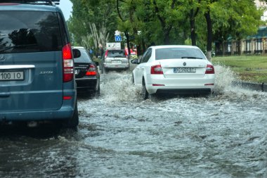 Odessa, Ukrayna -9 Ağustos 2019: sağanak yağışların neden olduğu sel felaketi sırasında su lar altında kalan yolda araba sürmek. Arabalar su üzerinde yüzüyor, sokakları su basayor. Arabaya sıçrat. Büyük bir su birikintisi ile sular altında şehir yolu