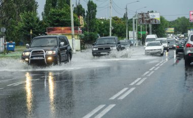 Odessa, Ukrayna - 9 Ağustos 2019: sağanak yağışların neden olduğu sel felaketi sırasında su lar altında kalan yolda araba sürmek. Arabalar su üzerinde yüzüyor, sokakları su basayor. Arabaya sıçrat. Büyük bir su birikintisi ile sular altında şehir yolu
