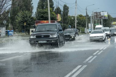 Odessa, Ukrayna - 9 Ağustos 2019: sağanak yağışların neden olduğu sel felaketi sırasında su lar altında kalan yolda araba sürmek. Arabalar su üzerinde yüzüyor, sokakları su basayor. Arabaya sıçrat. Büyük bir su birikintisi ile sular altında şehir yolu