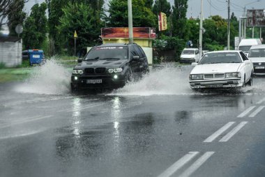 Odessa, Ukrayna - 9 Ağustos 2019: sağanak yağışların neden olduğu sel felaketi sırasında su lar altında kalan yolda araba sürmek. Arabalar su üzerinde yüzüyor, sokakları su basayor. Arabaya sıçrat. Büyük bir su birikintisi ile sular altında şehir yolu