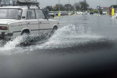 Odessa, Ukrayna - 9 Ağustos 2019: sağanak yağışların neden olduğu sel felaketi sırasında su lar altında kalan yolda araba sürmek. Arabalar su üzerinde yüzüyor, sokakları su basayor. Arabaya sıçrat. Büyük bir su birikintisi ile sular altında şehir yolu