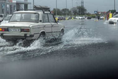 Odessa, Ukrayna - 9 Ağustos 2019: sağanak yağışların neden olduğu sel felaketi sırasında su lar altında kalan yolda araba sürmek. Arabalar su üzerinde yüzüyor, sokakları su basayor. Arabaya sıçrat. Büyük bir su birikintisi ile sular altında şehir yolu