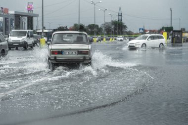 Odessa, Ukrayna - 9 Ağustos 2019: sağanak yağışların neden olduğu sel felaketi sırasında su lar altında kalan yolda araba sürmek. Arabalar su üzerinde yüzüyor, sokakları su basayor. Arabaya sıçrat. Büyük bir su birikintisi ile sular altında şehir yolu