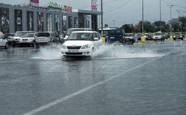 Odessa, Ukrayna - 9 Ağustos 2019: sağanak yağışların neden olduğu sel felaketi sırasında su lar altında kalan yolda araba sürmek. Arabalar su üzerinde yüzüyor, sokakları su basayor. Arabaya sıçrat. Büyük bir su birikintisi ile sular altında şehir yolu