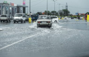 Odessa, Ukrayna - 9 Ağustos 2019: sağanak yağışların neden olduğu sel felaketi sırasında su lar altında kalan yolda araba sürmek. Arabalar su üzerinde yüzüyor, sokakları su basayor. Arabaya sıçrat. Büyük bir su birikintisi ile sular altında şehir yolu