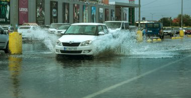 Odessa, Ukrayna - 9 Ağustos 2019: sağanak yağışların neden olduğu sel felaketi sırasında su lar altında kalan yolda araba sürmek. Arabalar su üzerinde yüzüyor, sokakları su basayor. Arabaya sıçrat. Büyük bir su birikintisi ile sular altında şehir yolu