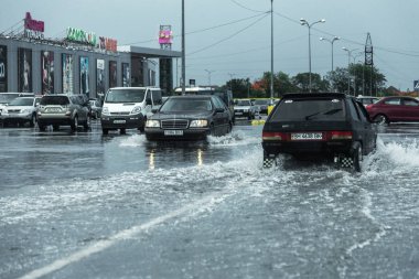 Odessa, Ukrayna - 9 Ağustos 2019: sağanak yağışların neden olduğu sel felaketi sırasında su lar altında kalan yolda araba sürmek. Arabalar su üzerinde yüzüyor, sokakları su basayor. Arabaya sıçrat. Büyük bir su birikintisi ile sular altında şehir yolu