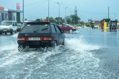 Odessa, Ukrayna - 9 Ağustos 2019: sağanak yağışların neden olduğu sel felaketi sırasında su lar altında kalan yolda araba sürmek. Arabalar su üzerinde yüzüyor, sokakları su basayor. Arabaya sıçrat. Büyük bir su birikintisi ile sular altında şehir yolu