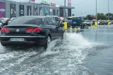 Odessa, Ukrayna - 9 Ağustos 2019: sağanak yağışların neden olduğu sel felaketi sırasında su lar altında kalan yolda araba sürmek. Arabalar su üzerinde yüzüyor, sokakları su basayor. Arabaya sıçrat. Büyük bir su birikintisi ile sular altında şehir yolu