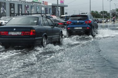 Odessa, Ukrayna - 9 Ağustos 2019: sağanak yağışların neden olduğu sel felaketi sırasında su lar altında kalan yolda araba sürmek. Arabalar su üzerinde yüzüyor, sokakları su basayor. Arabaya sıçrat. Büyük bir su birikintisi ile sular altında şehir yolu