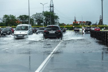 Odessa, Ukrayna - 9 Ağustos 2019: sağanak yağışların neden olduğu sel felaketi sırasında su lar altında kalan yolda araba sürmek. Arabalar su üzerinde yüzüyor, sokakları su basayor. Arabaya sıçrat. Büyük bir su birikintisi ile sular altında şehir yolu