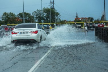 Odessa, Ukrayna - 9 Ağustos 2019: sağanak yağışların neden olduğu sel felaketi sırasında su lar altında kalan yolda araba sürmek. Arabalar su üzerinde yüzüyor, sokakları su basayor. Arabaya sıçrat. Büyük bir su birikintisi ile sular altında şehir yolu