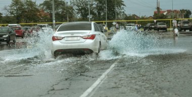 Odessa, Ukrayna - 9 Ağustos 2019: sağanak yağışların neden olduğu sel felaketi sırasında su lar altında kalan yolda araba sürmek. Arabalar su üzerinde yüzüyor, sokakları su basayor. Arabaya sıçrat. Büyük bir su birikintisi ile sular altında şehir yolu