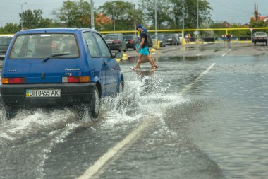 Odessa, Ukrayna - 9 Ağustos 2019: sağanak yağışların neden olduğu sel felaketi sırasında su lar altında kalan yolda araba sürmek. Arabalar su üzerinde yüzüyor, sokakları su basayor. Arabaya sıçrat. Büyük bir su birikintisi ile sular altında şehir yolu