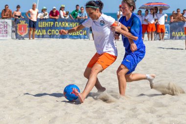 Odessa, Ukrayna-Temmuz 21, 2019: Plajda amatör kadınlar arasında Plaj Futbolu Şampiyonası. Kumda futbol. Genç güzel kızlar şehir plajı kum üzerinde plaj futbol oynarken. Kumüzerinde futbol