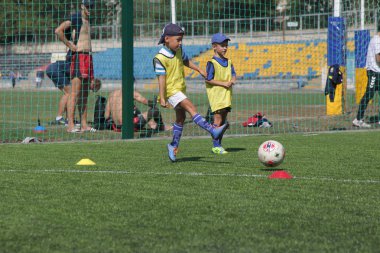 Odessa, Ukrayna - 7 Eylül 2019: Antrenmanda küçük çocuklar futbol oynuyor. Genç çocuklar oyun alanında futbol uyguluyorlar. Çocuklar yeşil futsal sahada futbol oynuyor