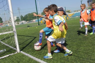 Odessa, Ukrayna - 7 Eylül 2019: Antrenmanda küçük çocuklar futbol oynuyor. Genç çocuklar oyun alanında futbol uyguluyorlar. Çocuklar yeşil futsal sahada futbol oynuyor