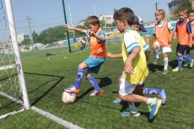 Odessa, Ukrayna - 7 Eylül 2019: Antrenmanda küçük çocuklar futbol oynuyor. Genç çocuklar oyun alanında futbol uyguluyorlar. Çocuklar yeşil futsal sahada futbol oynuyor