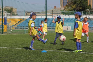 Odessa, Ukrayna - 7 Eylül 2019: Antrenmanda küçük çocuklar futbol oynuyor. Genç çocuklar oyun alanında futbol uyguluyorlar. Çocuklar yeşil futsal sahada futbol oynuyor