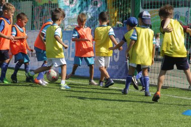 Odessa, Ukrayna - 7 Eylül 2019: Antrenmanda küçük çocuklar futbol oynuyor. Genç çocuklar oyun alanında futbol uyguluyorlar. Çocuklar yeşil futsal sahada futbol oynuyor