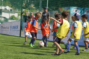 Odessa, Ukrayna - 7 Eylül 2019: Antrenmanda küçük çocuklar futbol oynuyor. Genç çocuklar oyun alanında futbol uyguluyorlar. Çocuklar yeşil futsal sahada futbol oynuyor
