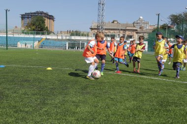 Odessa, Ukrayna - 7 Eylül 2019: Antrenmanda küçük çocuklar futbol oynuyor. Genç çocuklar oyun alanında futbol uyguluyorlar. Çocuklar yeşil futsal sahada futbol oynuyor
