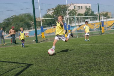 Odessa, Ukrayna - 7 Eylül 2019: Antrenmanda küçük çocuklar futbol oynuyor. Genç çocuklar oyun alanında futbol uyguluyorlar. Çocuklar yeşil futsal sahada futbol oynuyor
