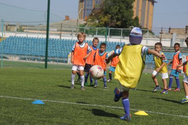 Odessa, Ukrayna - 7 Eylül 2019: Antrenmanda küçük çocuklar futbol oynuyor. Genç çocuklar oyun alanında futbol uyguluyorlar. Çocuklar yeşil futsal sahada futbol oynuyor