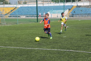 Odessa, Ukrayna - 7 Eylül 2019: Antrenmanda küçük çocuklar futbol oynuyor. Genç çocuklar oyun alanında futbol uyguluyorlar. Çocuklar yeşil futsal sahada futbol oynuyor