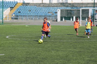 Odessa, Ukrayna - 7 Eylül 2019: Antrenmanda küçük çocuklar futbol oynuyor. Genç çocuklar oyun alanında futbol uyguluyorlar. Çocuklar yeşil futsal sahada futbol oynuyor