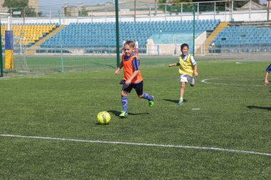 Odessa, Ukrayna - 7 Eylül 2019: Antrenmanda küçük çocuklar futbol oynuyor. Genç çocuklar oyun alanında futbol uyguluyorlar. Çocuklar yeşil futsal sahada futbol oynuyor