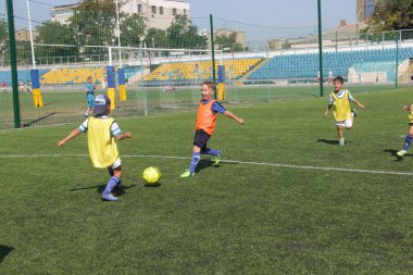 Odessa, Ukrayna - 7 Eylül 2019: Antrenmanda küçük çocuklar futbol oynuyor. Genç çocuklar oyun alanında futbol uyguluyorlar. Çocuklar yeşil futsal sahada futbol oynuyor