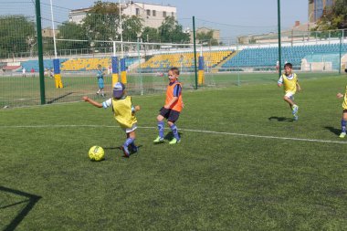 Odessa, Ukrayna - 7 Eylül 2019: Antrenmanda küçük çocuklar futbol oynuyor. Genç çocuklar oyun alanında futbol uyguluyorlar. Çocuklar yeşil futsal sahada futbol oynuyor