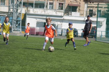 Odessa, Ukrayna - 7 Eylül 2019: Antrenmanda küçük çocuklar futbol oynuyor. Genç çocuklar oyun alanında futbol uyguluyorlar. Çocuklar yeşil futsal sahada futbol oynuyor