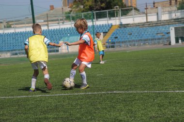 Odessa, Ukrayna - 7 Eylül 2019: Antrenmanda küçük çocuklar futbol oynuyor. Genç çocuklar oyun alanında futbol uyguluyorlar. Çocuklar yeşil futsal sahada futbol oynuyor